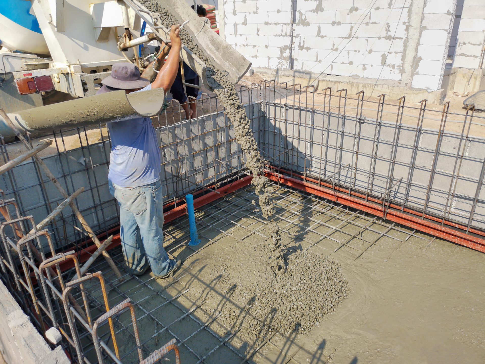 Arbeiter gießt Beton in die Stahlverstärkung für einen neuen Pool. 