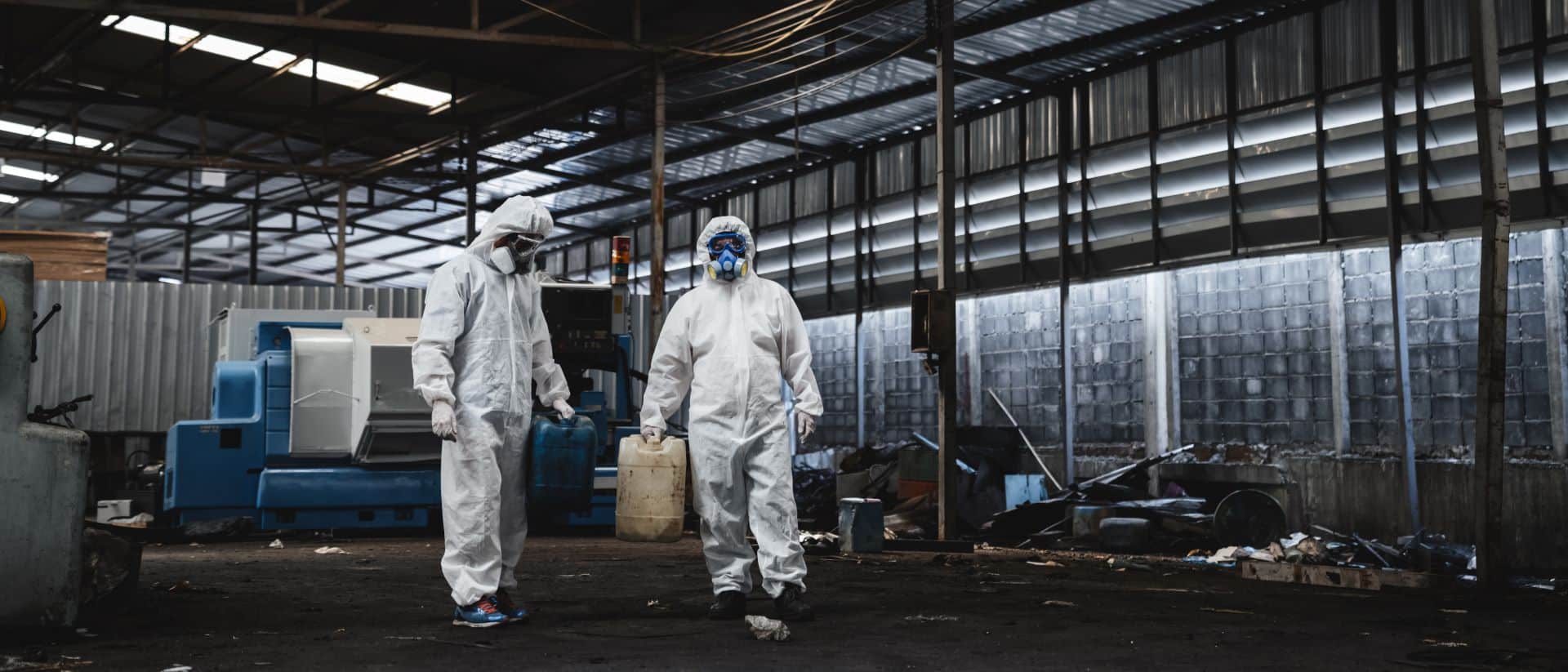 Arbeiter in Schutzanzügen und Masken in kontaminiertem Bereich.