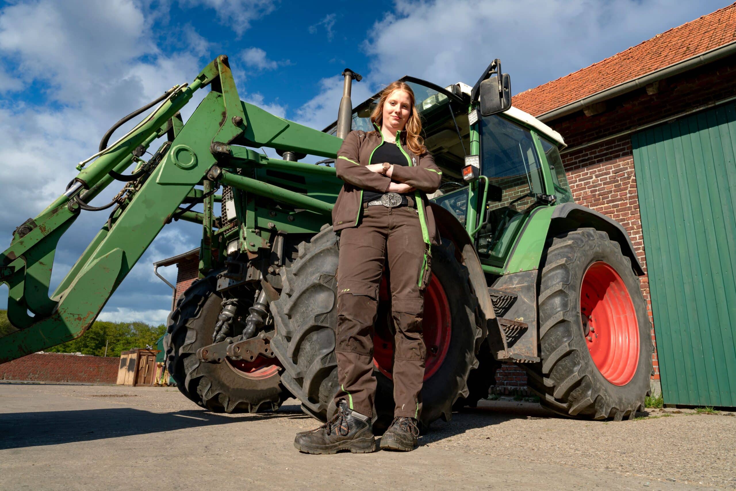 Landwirtin vor einem Traktor mit Frontlader auf einem Bauernhof