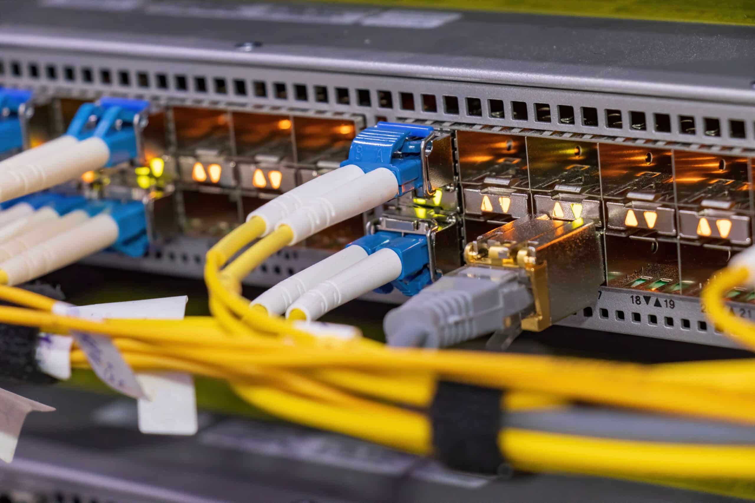 Netzwerk-Switch mit mehreren eingesteckten SFP Modulen und Glasfaserkabeln