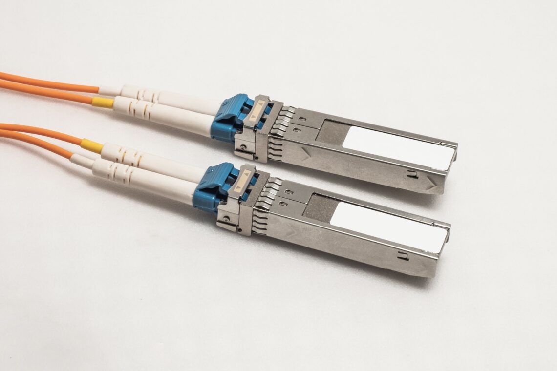 Zwei SFP Module mit angeschlossenen orangefarbenen Glasfaserkabeln