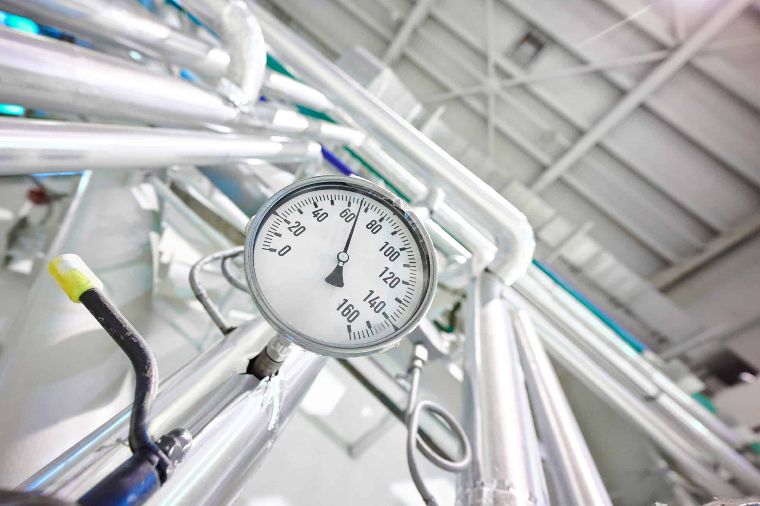 Temperaturanzeige an Industrieanlage mit Edelstahlleitungen – Symbol für hitzebeständige und temperaturbeständige Schlauchsysteme 