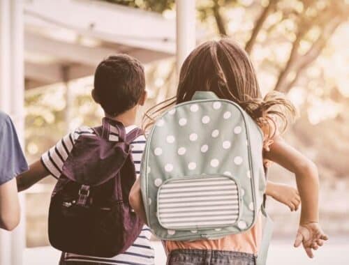 Drei Kinder mit Schulranzen auf dem Weg zur grundschule berlin bei Morgensonne