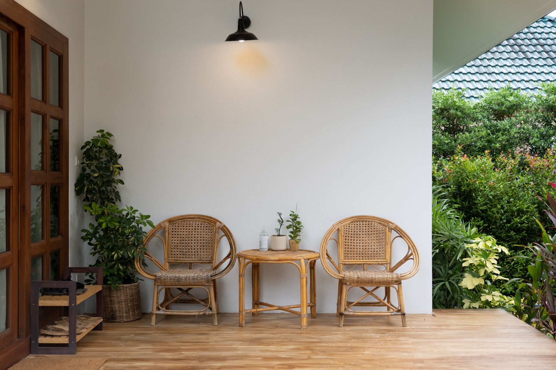 Heller Terrassenbereich mit Rattanmoebeln, Pflanzen und mediterranem Stil als Teil eines Gartens mit Pool